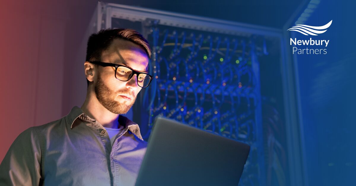 A man in glasses focuses on a laptop, analyzing data to enhance recruitment processes in staffing.