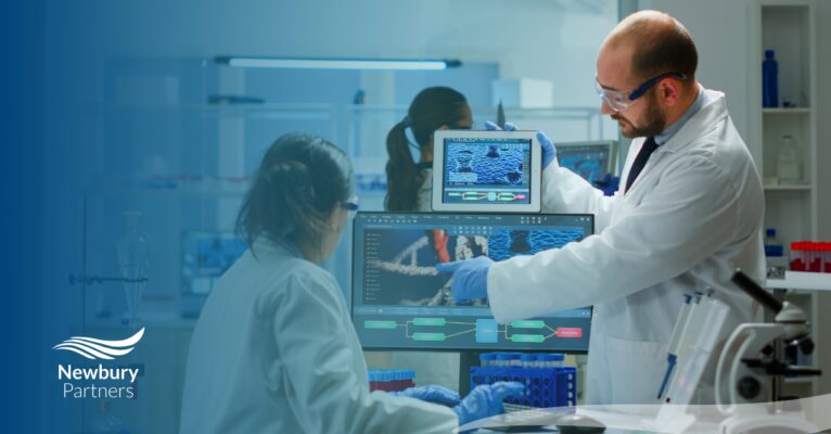 Two healthcare professionals in lab coats collaborate on a computer, addressing staffing technology challenges in healthcare.