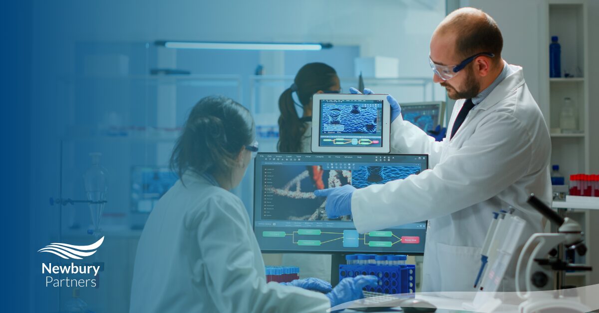 Two healthcare professionals in lab coats collaborate on a computer, addressing staffing technology challenges in healthcare.