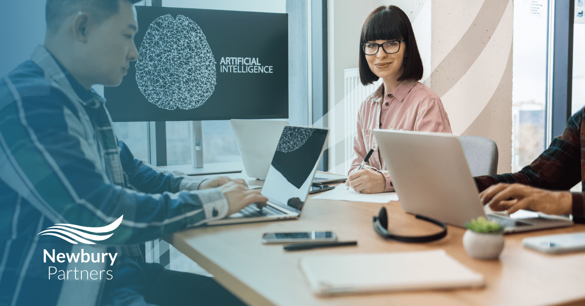 Staffing tech team discussing AI-driven recruitment strategies in a modern office, with 'Artificial Intelligence' displayed on screen – Newbury Partners branding visible.
