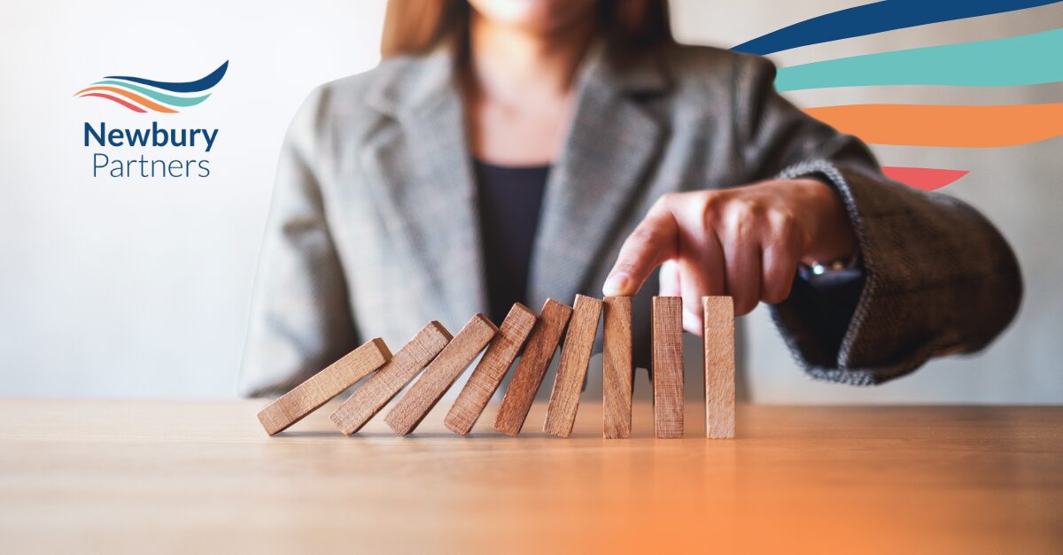 Business professional stopping domino effect with hand, illustrating how tech enablement prevents industry disruption