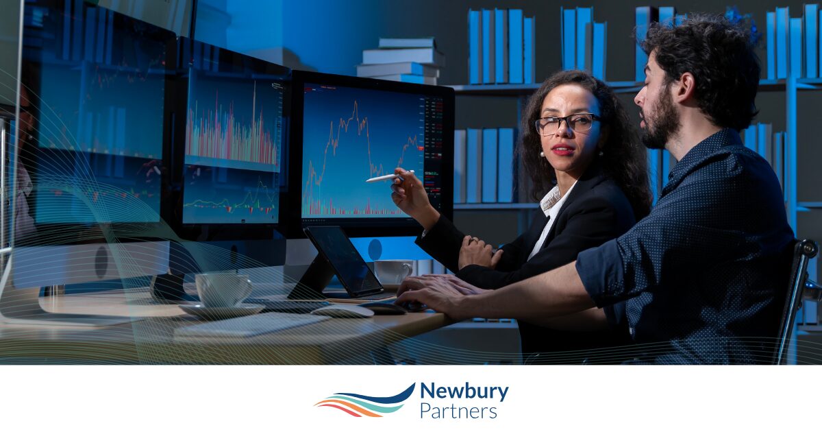 Business analysts reviewing data on multiple screens during staffing technology modernization planning session.