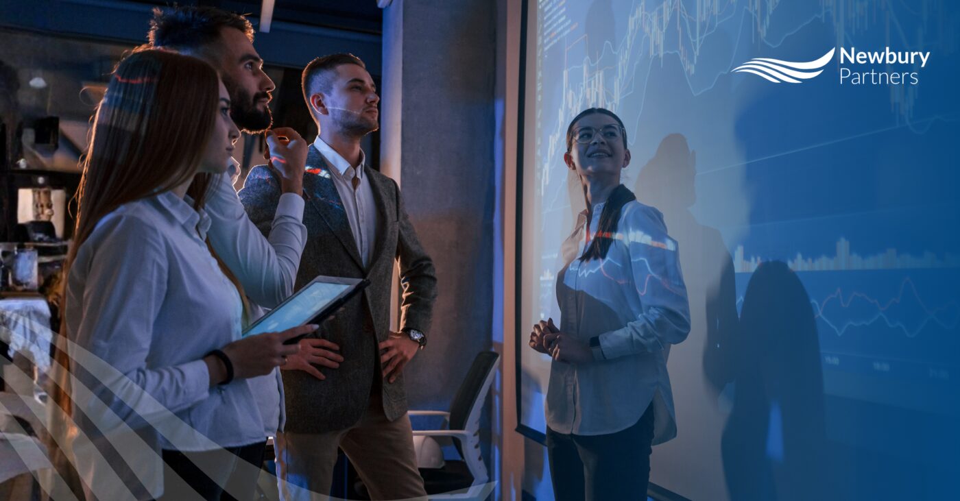 Staffing leadership team analyzing performance data on a large display screen to identify and resolve commissions disputes.